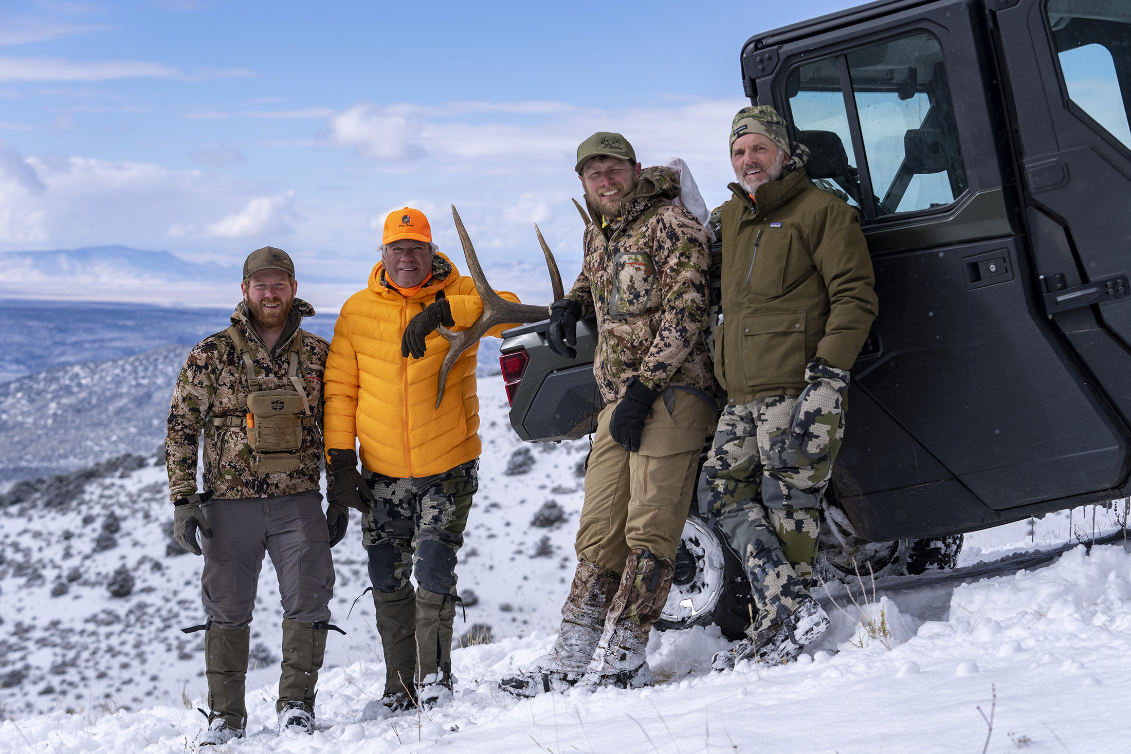 group of men in winter setting with elk in bed of pickup